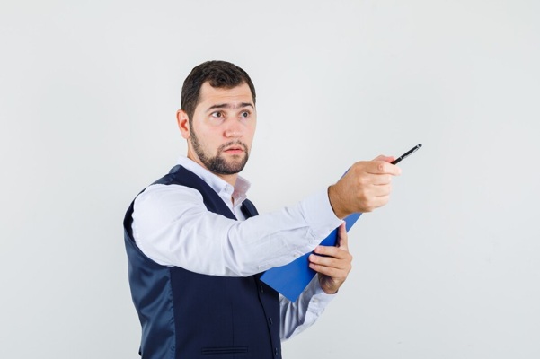 young-man-shirt-vest-pointing-away-while-holding-clipboard-looking-sensible_176474-16931.jpg