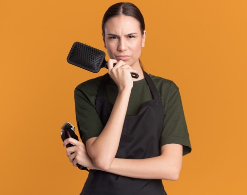 unpleased-young-brunette-barber-girl-uniform-holds-hair-clippers-comb_141793-103528.jpg