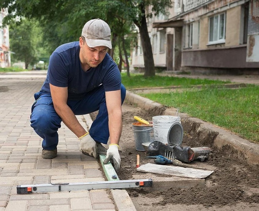 Рабочий на укладку тротуарной плитки