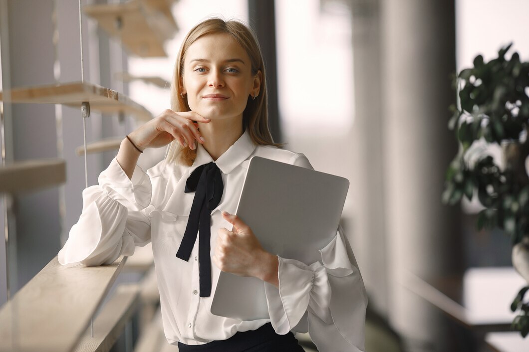 businesswoman-standing-office-with-laptop_1157-33420.jpg