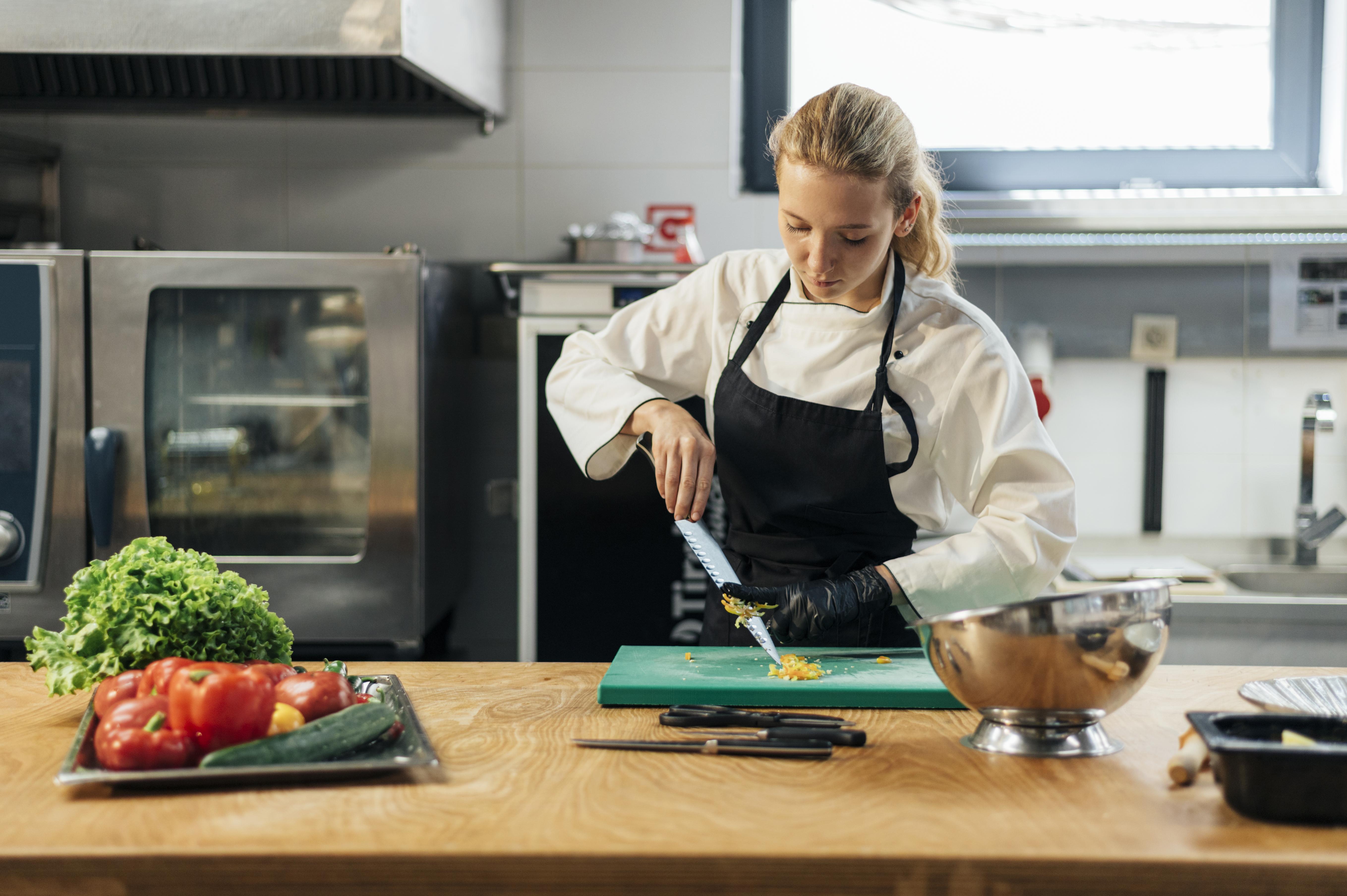 front-view-female-chef-kitchen-slicing-vegetables.jpg